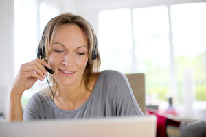 Portrait of woman with headset in front of laptop